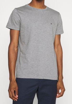 Camiseta de algodón gris con mangas cortas, cuello redondo y un pequeño logo bordado en el pecho. Textura suave y corte regular.