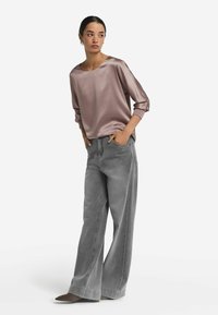 Top in satin color malva con maniche larghe abbinato a pantaloni a gamba larga grigio chiaro con vita alta e scarpe grigie a punta.