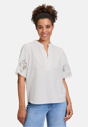 White, short-sleeved blouse with a mandarin collar, featuring floral embroidery on the sleeves and a relaxed fit. Smooth cotton fabric.