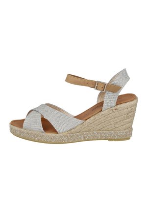 Sandalia de cuña con parte superior de textil plateado trenzado, correa para el tobillo beige y plataforma envuelta en yute. Diseño de punta abierta con correas entrecruzadas.