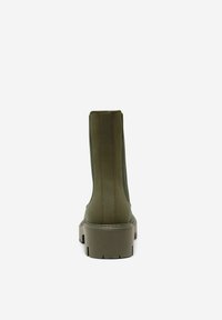 Bottine en cuir vert avec une semelle épaisse, dotée d'accents de coutures verticales et d'une texture lisse et mate.