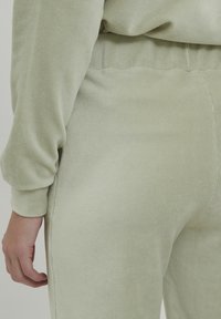 Loungewear set od kordura tkanine u svijetlozelenoj boji. Ima rebrastu teksturu, elastičnu futrolu i uski kroj s dugim rukavima.