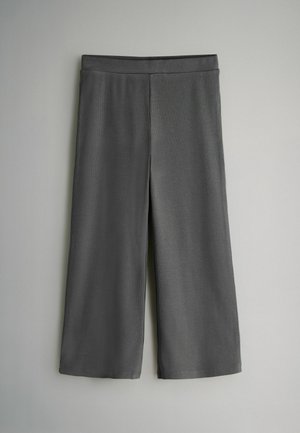 Šedé kalhoty culotte z hladké látky, s širokými nohavicemi a elastickým pasem pro pohodlí. Žádné viditelné vzory nebo detaily.