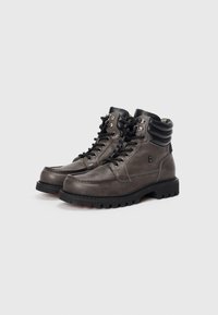 Bottines en cuir gris avec des accents noirs, col rembourré, bout rond, semelles en caoutchouc robustes et œillets en métal pour les lacets.