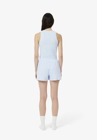 Top de tirantes azul claro y pantalones cortos a juego, hechos de una tela suave, con un corte holgado y cintura elástica. Incluye calcetines deportivos blancos.