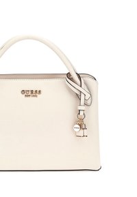 Borsa a mano color crema con un design strutturato, superficie testurizzata e dettagli metallici. Presenta un charm removibile e un logo decorativo.