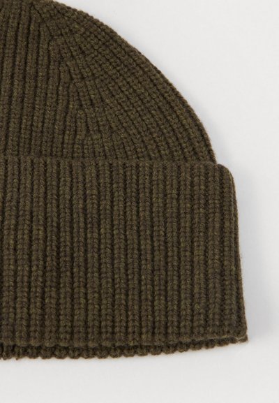 Beanie a coste verde oliva scuro con risvolto, fotografato su uno sfondo neutro chiaro.