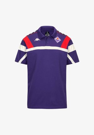 Polo viola con strisce diagonali bianche e rosse sulle spalle, una striscia orizzontale bianca sul petto e loghi sportivi ricamati.