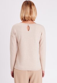 Beige strukturierter Pullover mit langen Ärmeln und einem Schlüssellochdetail am Rücken, mit rundem Ausschnitt und geripptem Saum.