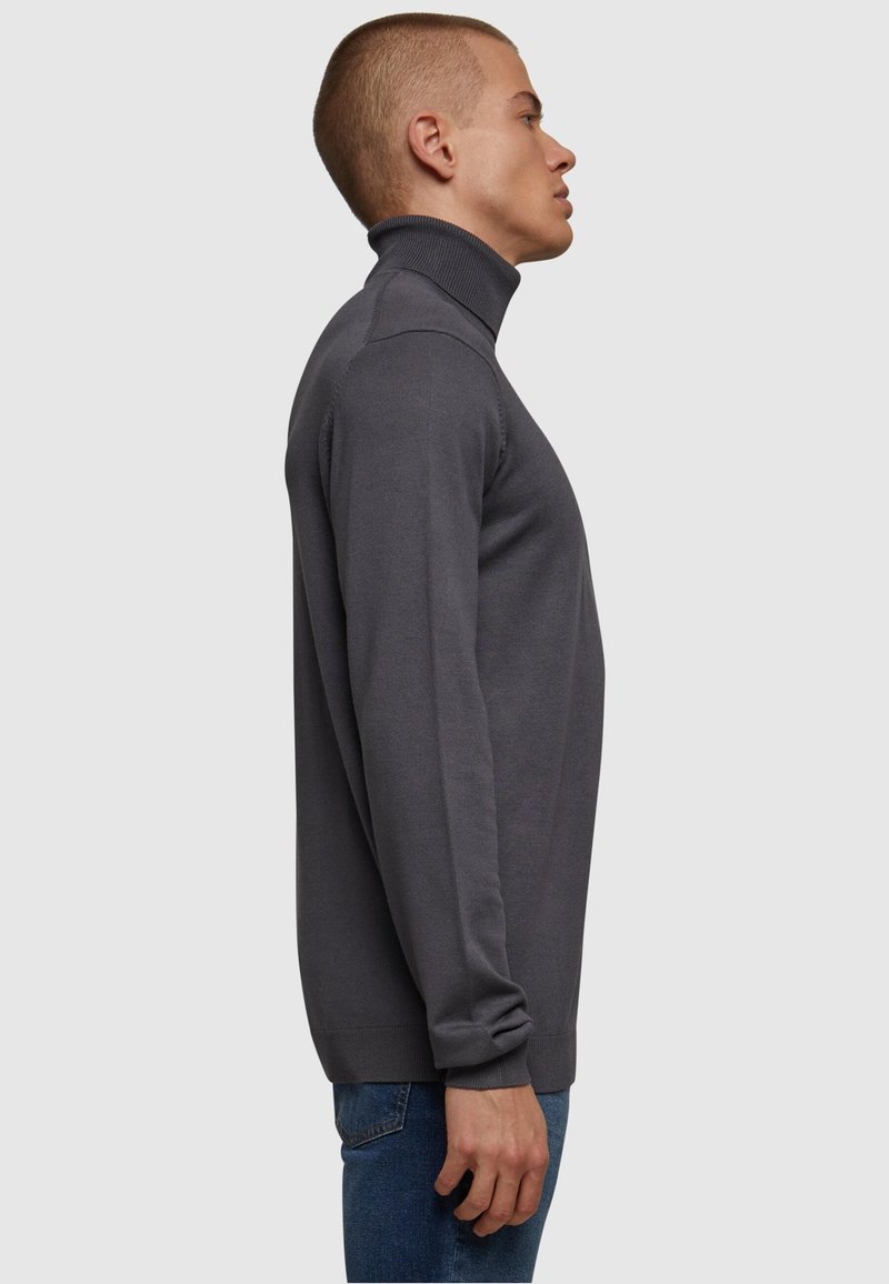 Dunkelgrauer Rollkragenpullover aus weichem Material, mit slim-Fit und gerippten Details am Kragen und an den Bündchen.