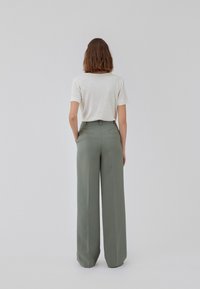 Light gray t-shirt with short sleeves paired with high-waisted, wide-leg pants in muted green, featuring back pockets and tailored design.