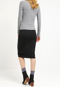 Gray long-sleeve ribbed shirt paired with a black pencil skirt. Black ankle boots with a stacked heel. Ribbed texture on both garments.