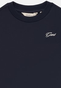 Marineblauwe crewneck sweatshirt met ribbelkraag en klein wit geborduurd "Gant" logo op de borst.