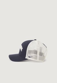 Jūras zila beisbola cepure ar beigei tīkla aizmuguri, kurai priekšā ir balti "NEW YORK" uzraksts un mazs Nike logo sānos.