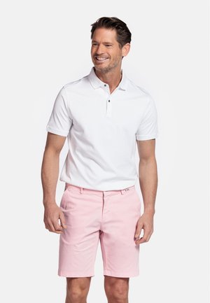 Witte polo met korte mouwen, drie knopen bij de halslijn, en groene accenten, gecombineerd met lichtroze shorts met omgeslagen zomen en zijzakken.