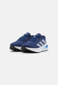 Des chaussures de course en mesh bleu avec une semelle blanche, présentant trois rayures diagonales grises et un accent bleu au niveau du talon. Surface texturée remarquable.