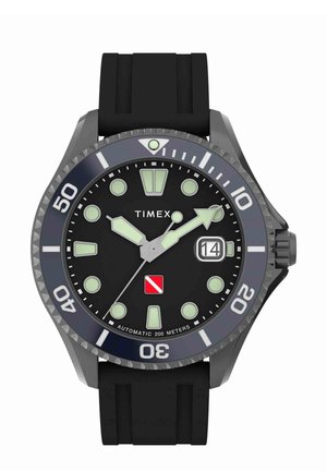 Montre de plongée noire avec un boîtier rond en acier inoxydable, des marqueurs lumineux et un affichage de la date. Dispose d'une lunette texturée et d'un bracelet en caoutchouc noir.