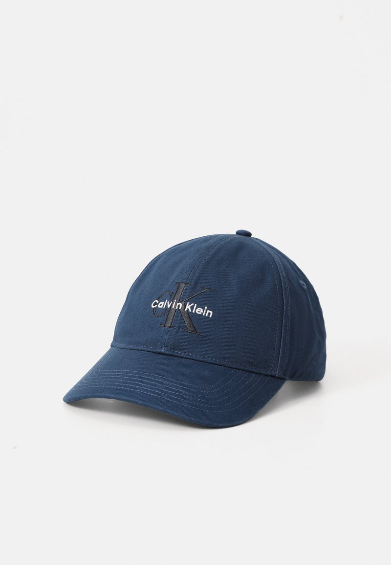 Navy blue cap made of cotton with a curved brim. Features embroidered "Calvin Klein" and "CK" logo on the front. Simple, structured design.