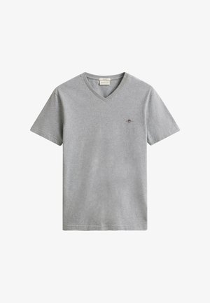 Jasnoszara koszulka z krótkim rękawem i dekoltem w serek, z małym wyszywanym logo na lewej stronie klatki piersiowej oraz materiałową metką marki wewnątrz kołnierza.