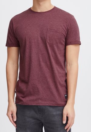 Bordeauxrotes T-Shirt mit kurzen Ärmeln aus weichem Stoff, mit einer Brusttasche und einem entspannten Schnitt. Der Saum ist gerade und mit einem kleinen Logoetikett versehen.