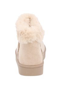 Botas tobilleras beige de suave ante con un collar de pelo sintético y una suela de goma ligera, con puntera redonda y textura suave.