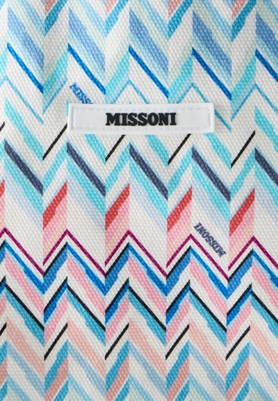 Ύφασμα με μοτίβο ζιγκ-ζαγκ σε αποχρώσεις του μπλε, ροζ και κόκκινου με μια λευκή ετικέτα στο κέντρο που αναγράφει «MISSONI».