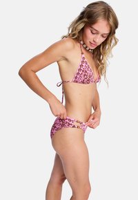 Różowy kwiatowy bikini, w tym trójkątny top z regulowanymi wiązaniami oraz dopasowane majtki z wycięciami i dekoracyjnymi elementami na bokach.