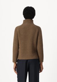 Brauner gerippter Rollkragenpullover mit figurbetontem Schnitt, langen Ärmeln und hohem Kragen. Strukturierter Strickstoff.