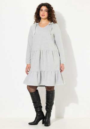 Grau Hoodie-Kleid aus weichem Stoff, mit langen Ärmeln, einem gestuften Rüschensaum und Zugbändern an der Kapuze, kombiniert mit knielangen schwarzen Stiefeln.