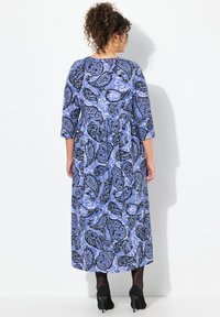 Vestido maxi de estampado paisley azul con mangas de tres cuartos, escote redondo y corte relajado. La tela tiene una textura suave y fluida.