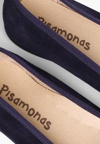 Ballerine in suede blu navy con bordi rigidi flessibili, dotate di una soletta beige con il marchio "Pisamonas" e una superficie morbida e testurizzata.