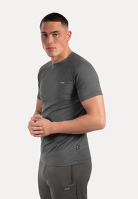 Grijze t-shirt met korte mouwen, gemaakt van gladde stof, met een ronde hals en een klein merketiket aan de voorkant links.
