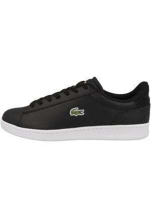 Baskets basses noires avec semelle blanche, lacets noirs et logo crocodile vert sur le côté, vues de l'extérieur.