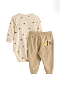 Bodysuit w desenie pszczółek w kolorze kremowym z długimi rękawami, w zestawie z beżowymi spodniami z haftowaną pszczółką. Miękka dzianina bawełniana, elastyczny pas.