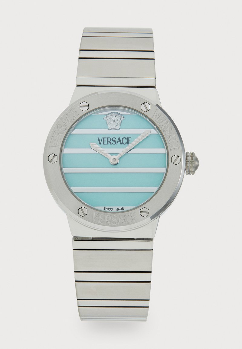 Relógio de aço inoxidável prateado com um mostrador redondo, mostrador listrado em turquesa e o logotipo "Versace" gravado. Apresenta acabamentos metálicos e uma bracelete lisa.