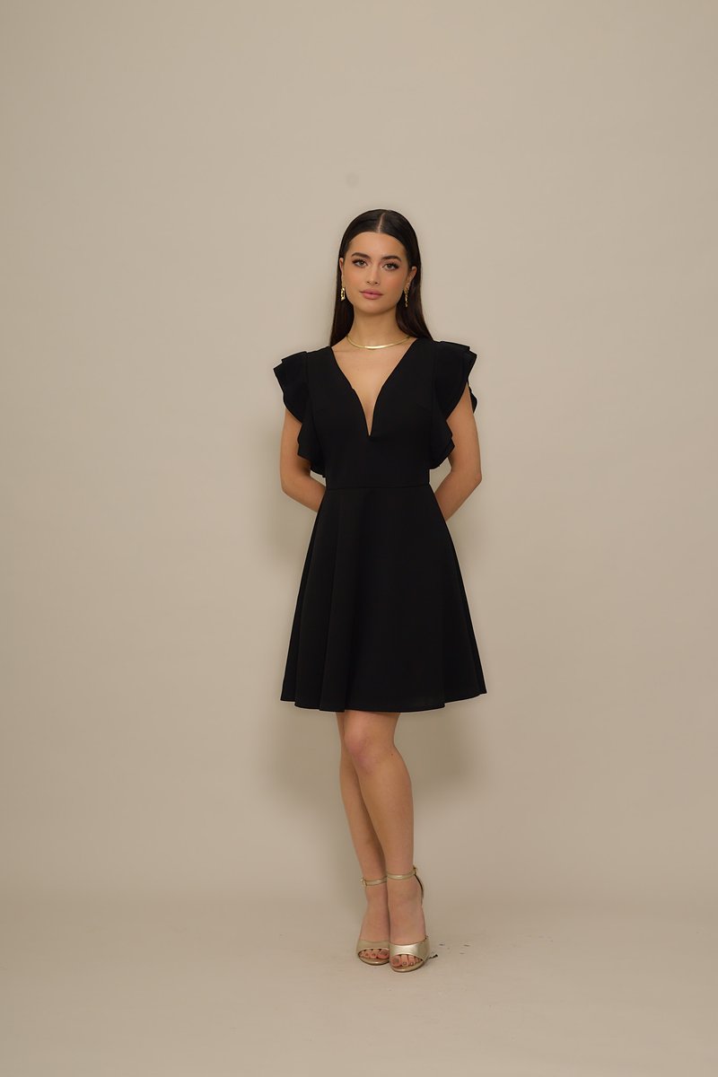 Black dress with ruffled sleeves, V-neckline, and fitted bodice; flared skirt, paired with gold ankle strap heels; smooth texture.
