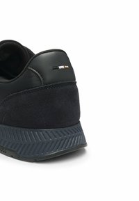 Baskets de sport marine avec une tige en suède et cuir, semelle en caoutchouc texturé et un talon distinct en caoutchouc avec un motif en zigzag. Présente un logo subtil.