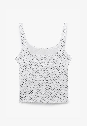 Top sin mangas blanco con lunares negros, con una textura de tela suave y un escote fruncido para añadir detalle.