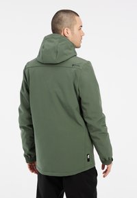 Grøn vandtæt jakke med hætte, elastiske manchetter og sidelommer. Har et logo på den øverste del af ryggen og en glat tekstur.