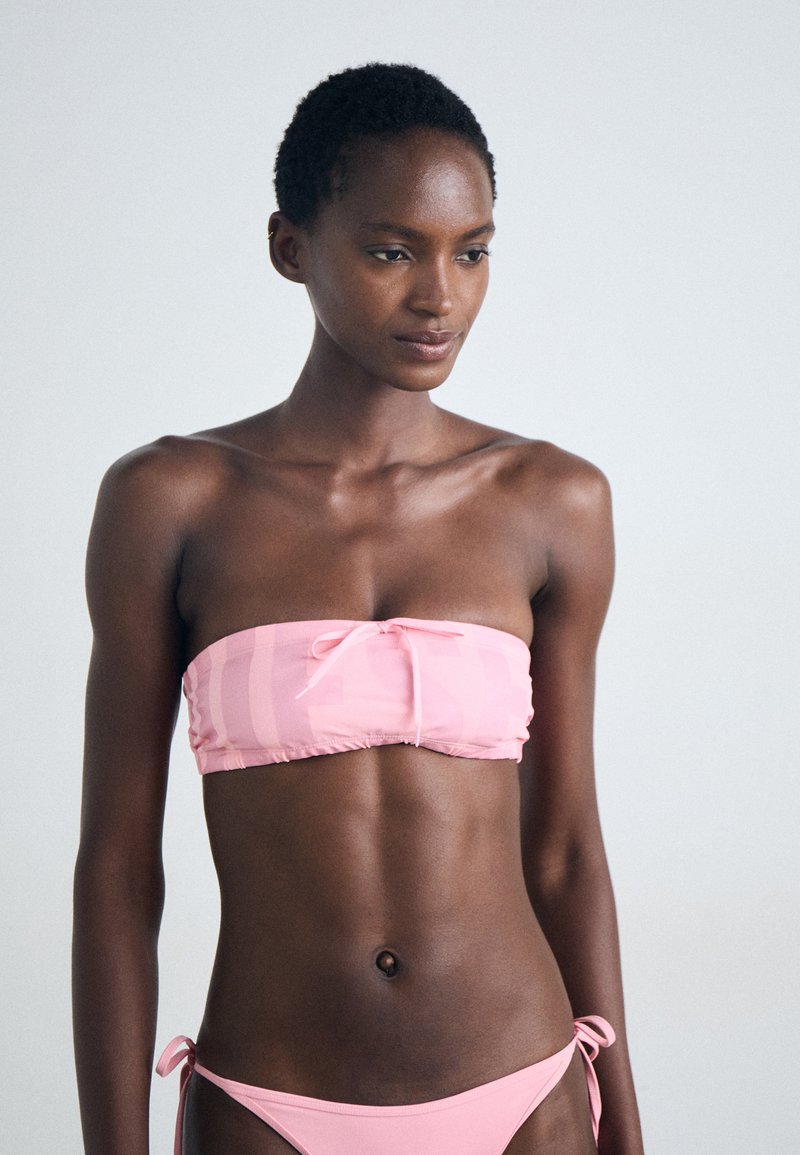 Rosa bandeau-bikini topp med en frontsløyfe og matchende sidesnøring-bunn. Glatt stoff med et subtilt stripemønster.
