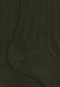 Calze a costine verde scuro con una texture morbida, forma allungata e aree rinforzate sulla punta e sul tallone per una maggiore durata.