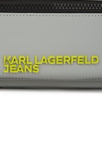 Borsa grigia con superficie testurizzata, caratterizzata da un logo embossato di un vivace giallo "KARL LAGERFELD JEANS" e un dettaglio della cerniera nera.