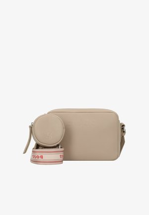 Sac bandoulière en cuir beige avec logo embouti, pochette à pièces ronde et sangle à motifs avec des accents rouges et blancs. Texture lisse.