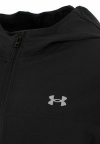 Chaqueta atlética negra hecha de tela texturizada, con cierre de cremallera y un logo gris en el área del pecho izquierdo. Diseño con capucha.