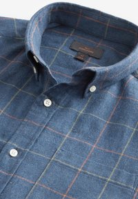 Camicia in flanella a quadri blu con colletto, caratterizzata da linee a griglia arancioni e gialle, chiusura con bottoni e un'etichetta con la scritta "NEXT SIGNATURE" in taglia M.