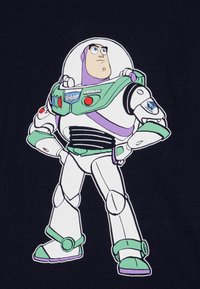 Grafikken viser Buzz Lightyear, en tegneserieastronaut i en hvit drakt med grønne og lilla detaljer, som står selvsikkert med hendene på hoftene.