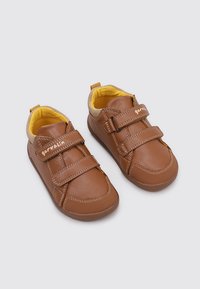 Chaussures pour enfants en cuir marron avec deux bandes Velcro, doublure intérieure jaune, design bas et semelles en caoutchouc pour une bonne adhérence et un confort optimal.