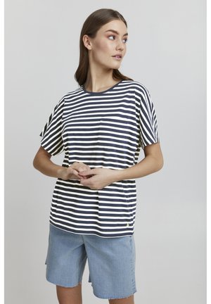 T-shirt w paski w kolorze granatowym i białym z krótkimi rękawami, okrągłym dekoltem i małą kieszonką po lewej stronie, w połączeniu z jasnymi szortami dżinsowymi.