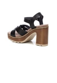 Sandalias de plataforma negras con tiras entrecruzadas, plantilla acolchada y un tacón grueso marrón con una superficie exterior texturizada.