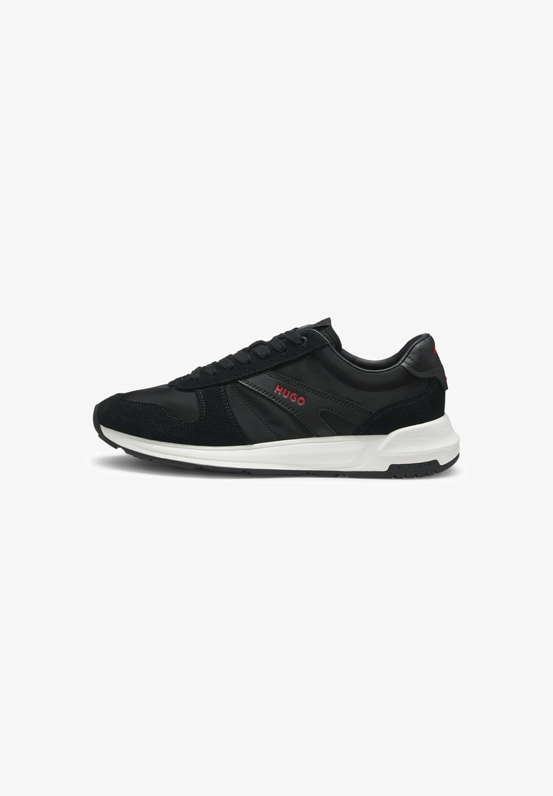 Baskets basses noires avec semelle blanche, panneaux en suède et cuir, logo rouge "HUGO" sur le côté et le talon, fermeture à lacets.